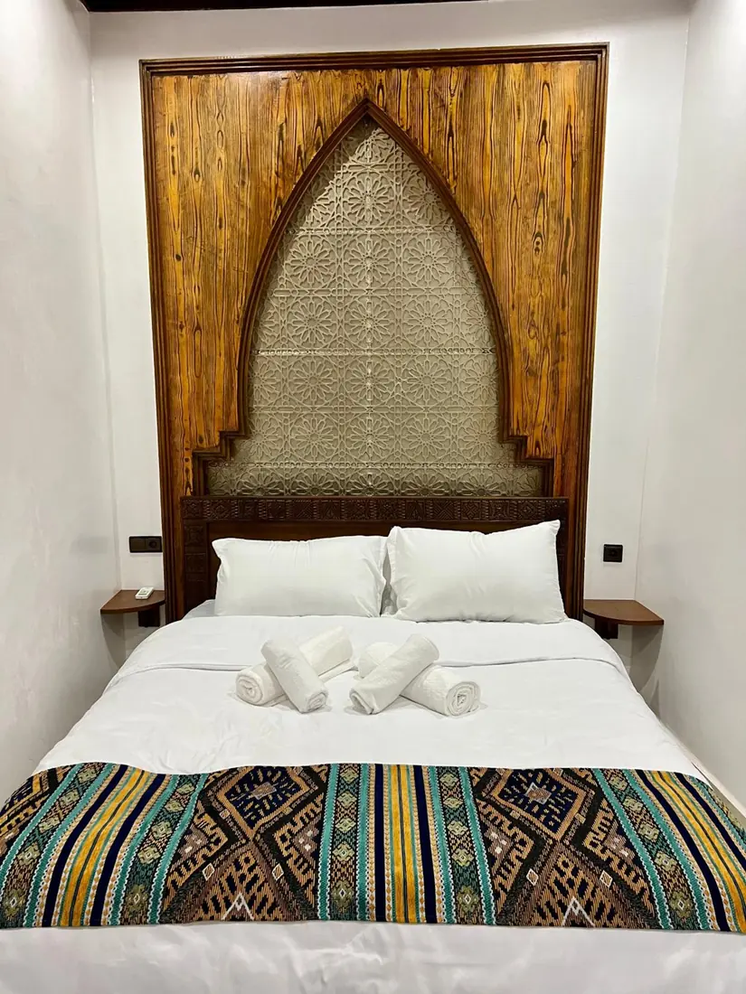 La Chambre Double Deluxe, sa tête de lit en arc de bois sculpté