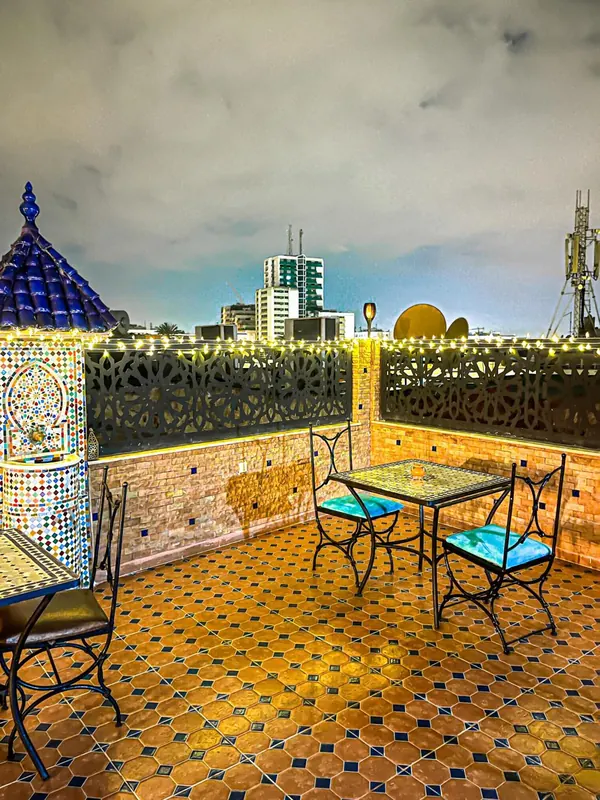 La terrasse sur le toit, tables de fer forgé et fontaine de zellige